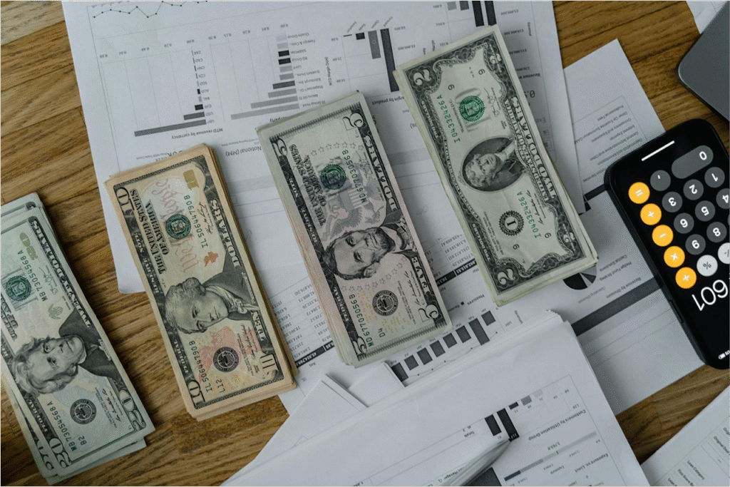 Stacks of US dollar bills with financial reports and calculator.