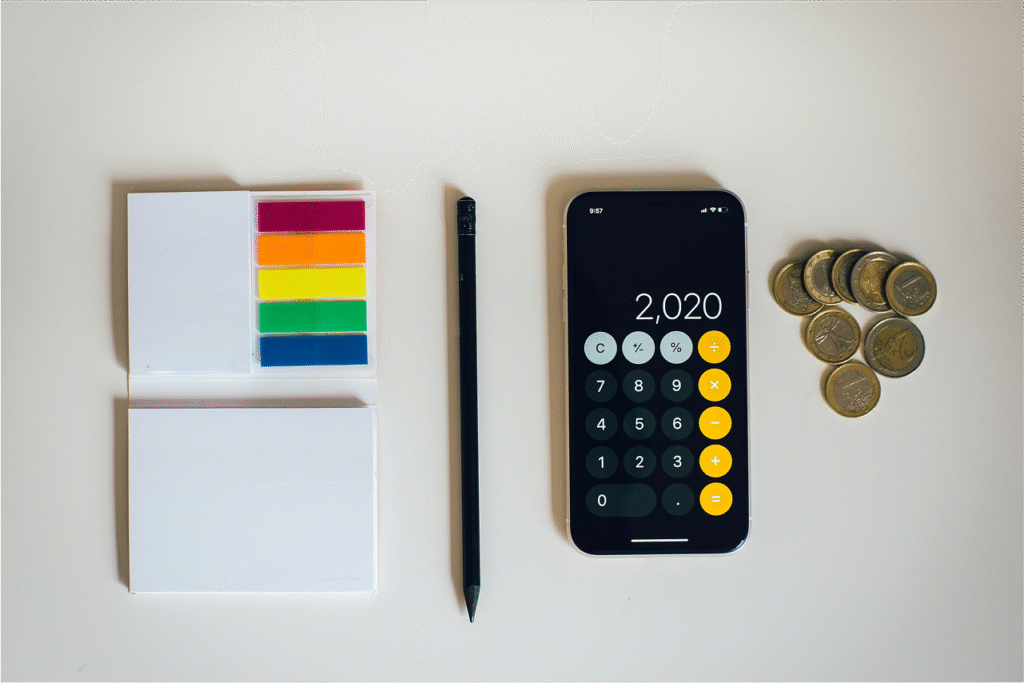 Calculator app on phone with coins and stationery items